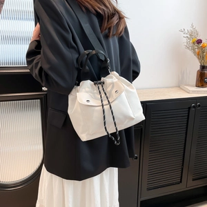 White minimalist drawstring bucket bag with shoulder strap and front snap pocket
