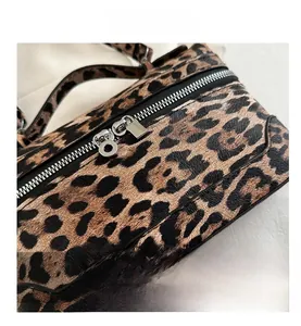 Detail view of leopard print bag with silver dual zippers and metallic padlock hardware