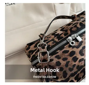 Close-up of durable metal zipper and hardware hook on leopard print crossbody bag