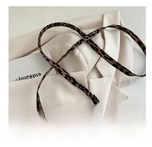 Close-up of leopard print shoulder strap with adjustable silver metal buckle on handbag