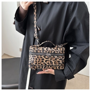 Close-up of leopard print crossbody bag featuring textured leather and dual zippers
