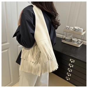 Detail of soft cream tassel handbag showing pebbled leather texture and layered fringe