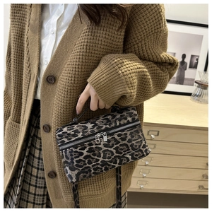 Close-up of leopard print crossbody bag with silver double zippers and matching handle