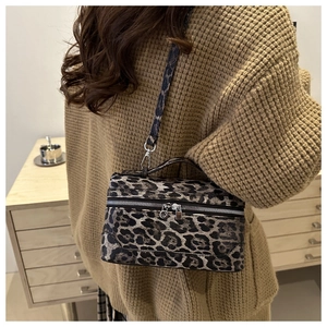 Side view of leopard print crossbody bag worn with a brown knit sweater in a cozy setting