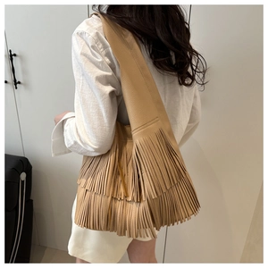 Detailed side view of apricot leather tassel shoulder bag showing bohemian fringe texture