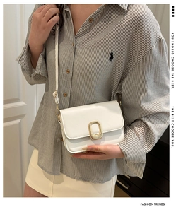 Close-up of white minimalist flap shoulder bag with elegant gold oval metal clasp closure