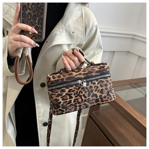 Close-up of leopard print crossbody bag with silver zippers and textured leather