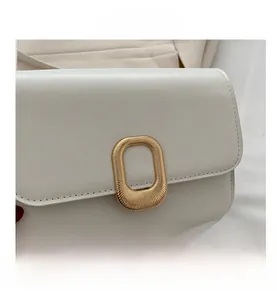 Close-up of creamy white leather square bag with decorative gold metal buckle