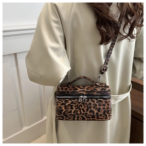 Close-up of leopard print crossbody bag featuring metal zippers and textured top handle