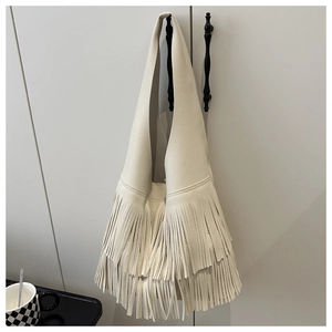 Detail of bohemian fringe and lychee texture on the cream white hobo shoulder bag