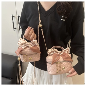 Detail of pink quilted bucket bag with chain strap, camellia charm and leopard silk bow