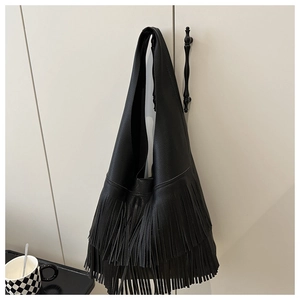 Detail of black pebbled leather tote bag featuring long fringes and bohemian tassels