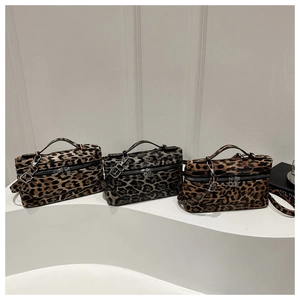 Three leopard print makeup bags with zipper closures and handles on a white display stand