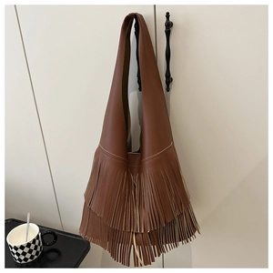 Detail of a brown lychee pattern leather tote bag with stylish long tassel fringe decor