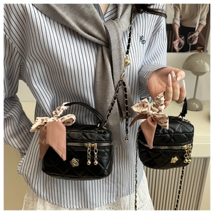 Close-up of black quilted vanity bags with gold floral accents and stylish silk ribbons