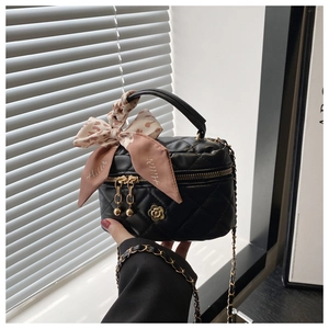 Detail of quilted leather mini bucket bag with gold flower charm and leopard print ribbon