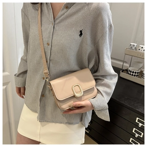 Detail shot of a beige crossbody square bag with a prominent golden metallic buckle