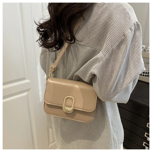 Detail of beige rectangular crossbody bag with vintage gold oval buckle on flap