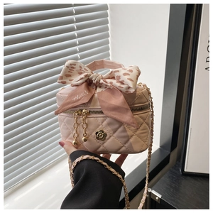 Detail of pink quilted mini bucket bag with ribbon bow and gold camellia ornament