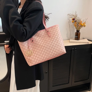 Pink tote bag with all-over M-letter print and gold charm shown in modern home setting