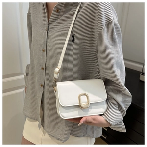 Close-up of a white minimalist leather crossbody bag with vintage gold metal clasp detail