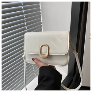 Detail of the white rectangular crossbody bag with a gold oval sunburst buckle and strap