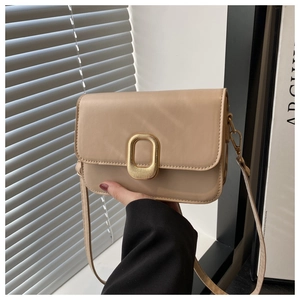 Detail of light beige leather crossbody bag featuring a golden oval ripple metal buckle