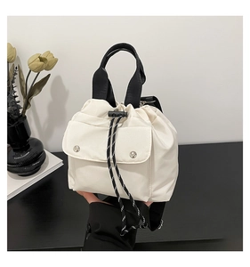 Detail der cremeweißen Nylon-Beuteltasche mit silbernen Druckknöpfen und Tragegriff