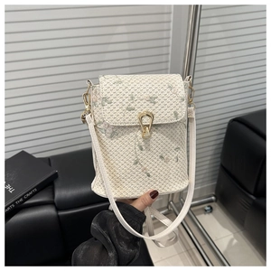 Dettaglio del ricamo floreale e fibbia dorata su una borsa a tracolla intrecciata bianca