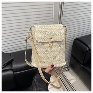 Dettaglio della borsa a tracolla in paglia beige con ricami floreali e chiusura in metallo dorato