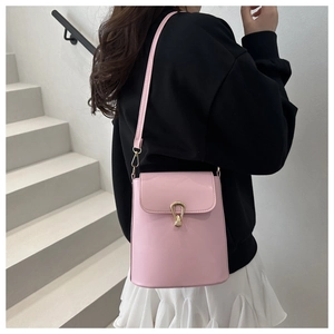Pink bucket bag with golden buckle and sleek leather texture on a white staircase