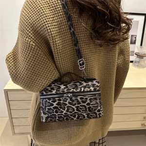 Vintage leopard print crossbody bag with top handle and silver hardware in interior setting