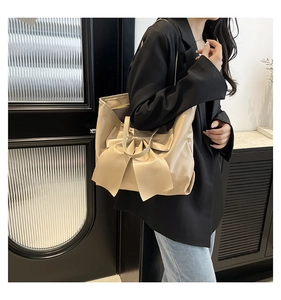 Modèle portant un grand sac cabas abricot avec nœud décoratif dans un décor intérieur