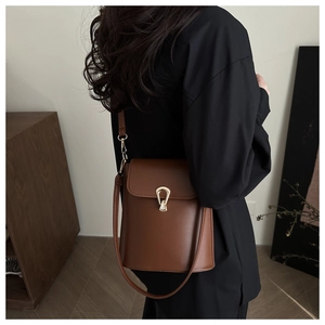 Detail of dark brown vintage bucket bag featuring a golden horseshoe clasp and slim strap