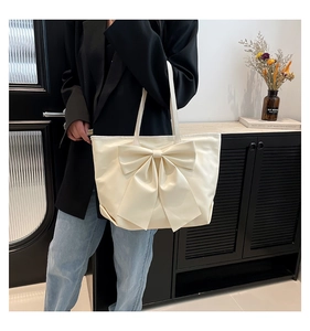 Détail d'un grand sac fourre-tout beige avec nœud décoratif porté à l'épaule