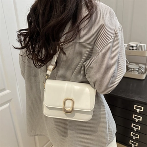 Minimalist cream white crossbody bag with polished gold oval buckle on smooth leather