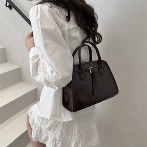 Classic dark brown tote bag in glossy faux leather worn with a white summer dress