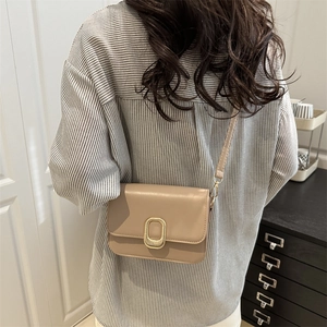 Elegant beige leather crossbody square bag with a textured gold oval buckle on top cover