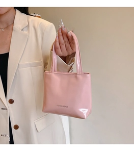 Détail du sac cabas en cuir verni rose avec texte mode et poignées élégantes