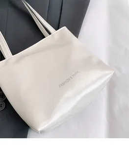 Détail d'un sac cabas blanc crème avec texture en cuir froissé et texte argenté imprimé