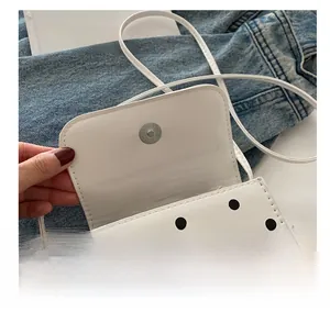 Détail du fermoir magnétique en métal sur le sac à bandoulière blanc à pois noirs