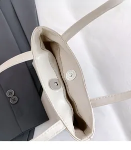 Détail du fermoir magnétique en argent et du cuir texturé crème du sac à main épuré