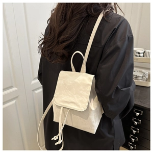 Vue détaillée d'un mini sac à dos blanc avec texture plissée porté par une femme