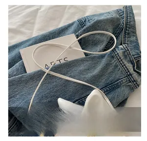Détail d'un sac bandoulière en similicuir blanc avec nœud élégant et bandoulière fine