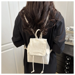 Vue de dos d'un mannequin portant un petit sac à dos en similicuir crème avec cordon