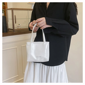 Gros plan du sac à main blanc en cuir verni brillant avec texte FASHION & BAGS décoratif