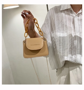 Detailansicht der beige Mini-Tasche mit gelber Acrylkette und goldenem Metall-Schultergurt