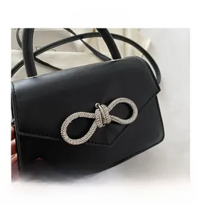 Detailed view of black textured faux leather bag featuring a large rhinestone bow buckle