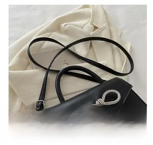Macro shot of black matte leather handbag with rhinestone bow detail and adjustable strap