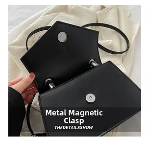 Detail of metal magnetic snap closure and fine stitching on black leather crossbody bag